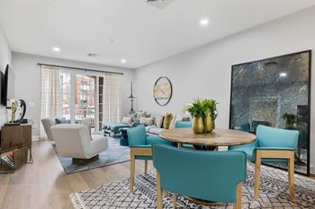 A living room with a large painting on the wall and a dining table with chairs around it.